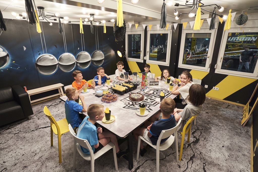 geburtstagsfeier wien - Kinder sitzen um einen Tisch und feiern eine Kindergeburtstagsfeier bei Jumpin Warrior