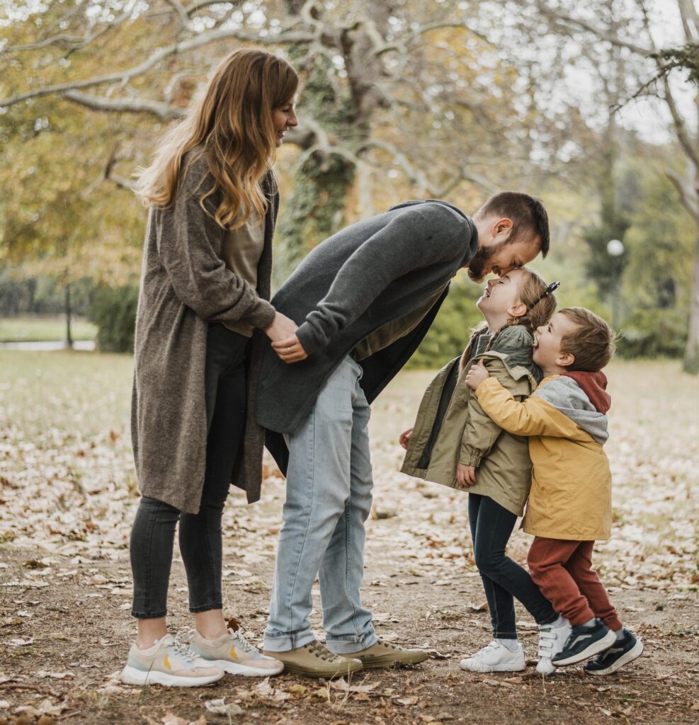 Familie lacht im Park mit zwei Kindern
