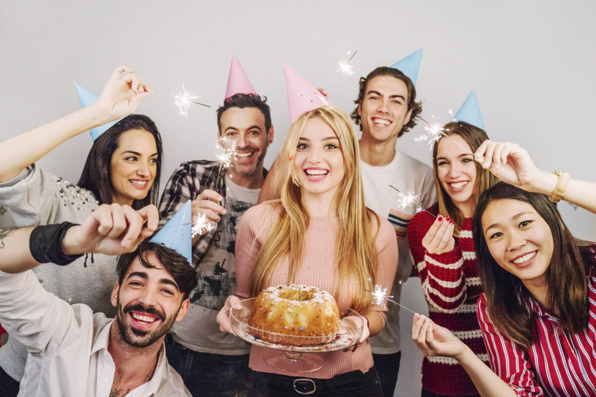 Gruppe von Freunden feiert eine Geburtstagsfeier mit Wunderkerzen und Kuchen