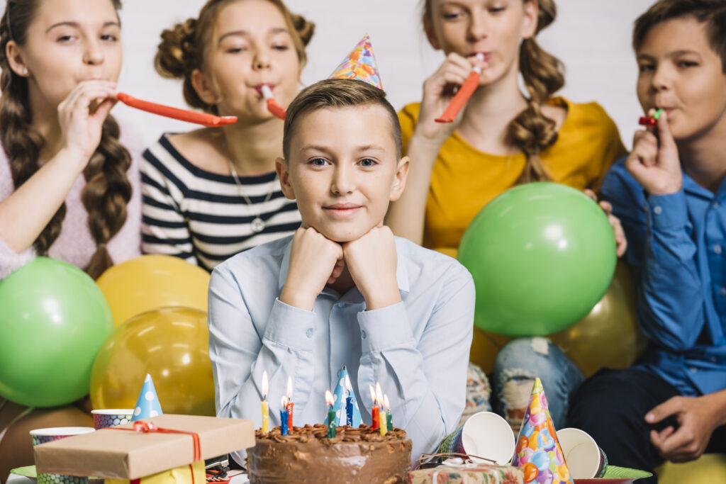 Kinder feiern fröhlich eine Geburtstagsfeier mit Partyhüten, Luftballons und Kuchen